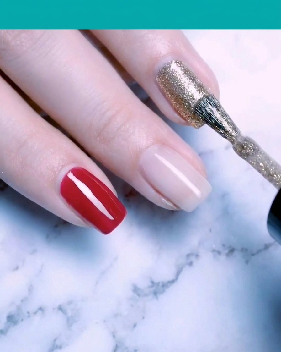 Un pinceau appliquant un vernis gel pailleté or fin et scintillant sur un ongle.