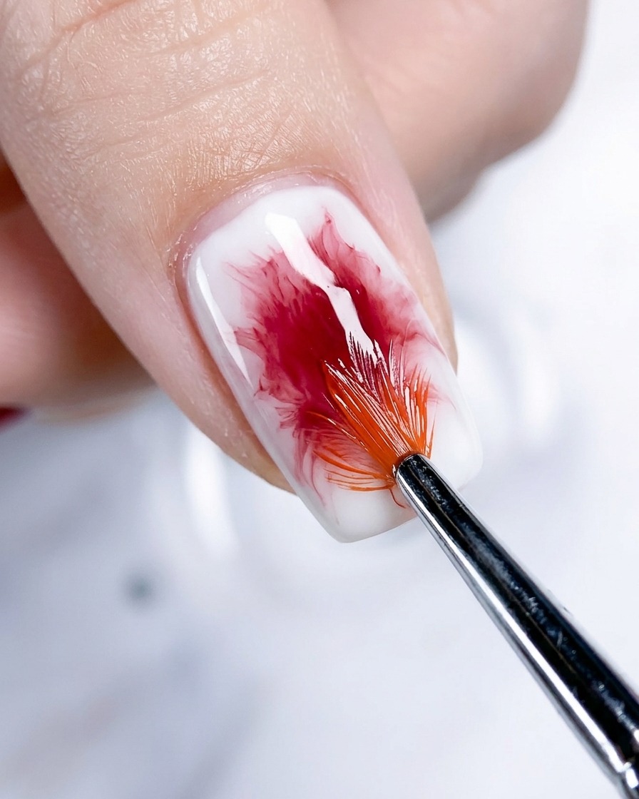 Gros plan dun ongle de pouce montrant leffet blush or rose étant estompé et approfondi avec un pinceau éventail.