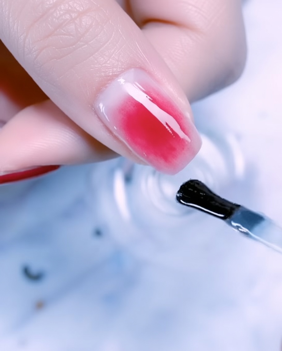 Gros plan dun ongle de pouce décoré de feuilles dor, daccents en fil métallique fin et de perles sur un dégradé or rose.