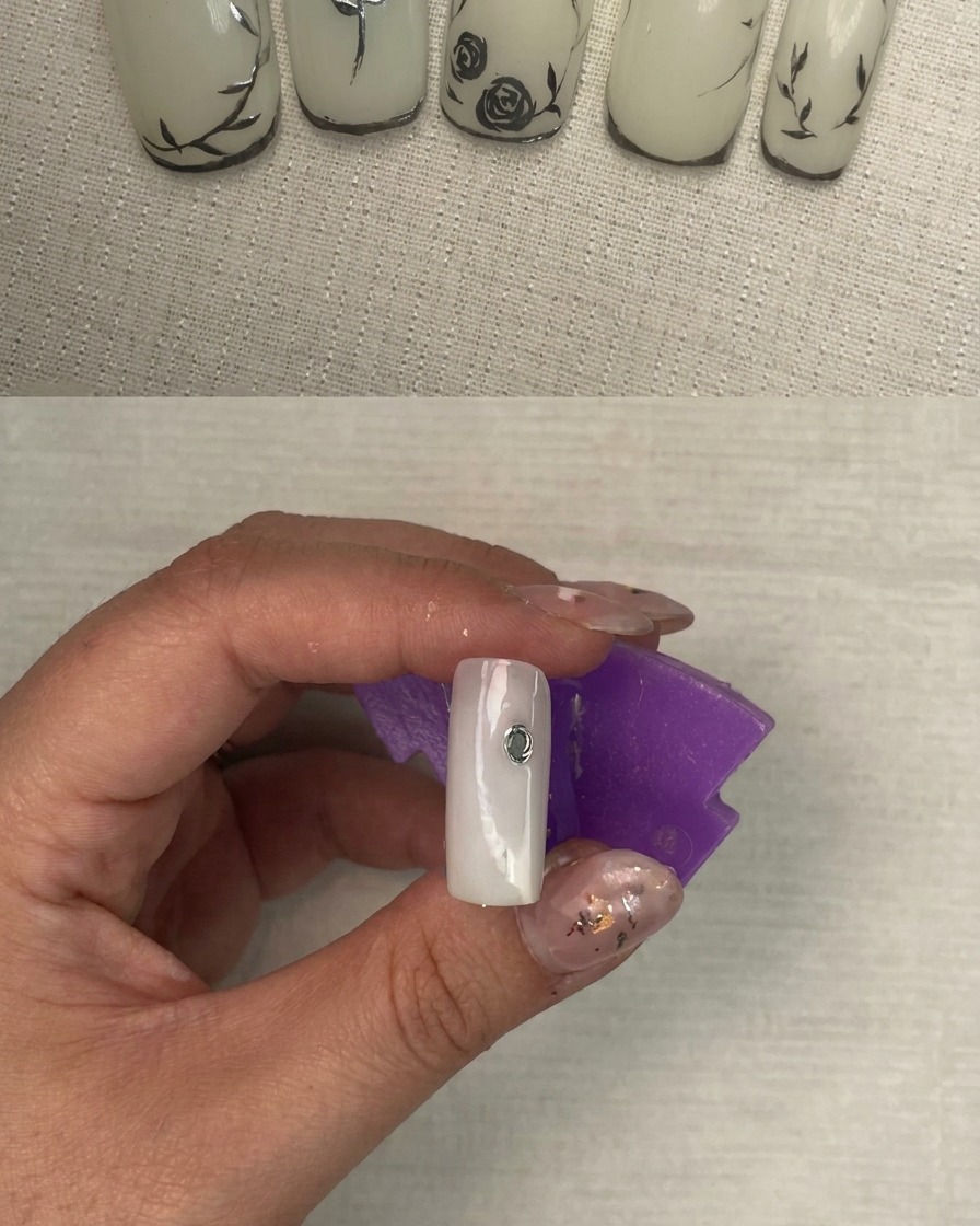 Un ongle montrant les traits argentés métalliques initiaux formant la base dun design floral.