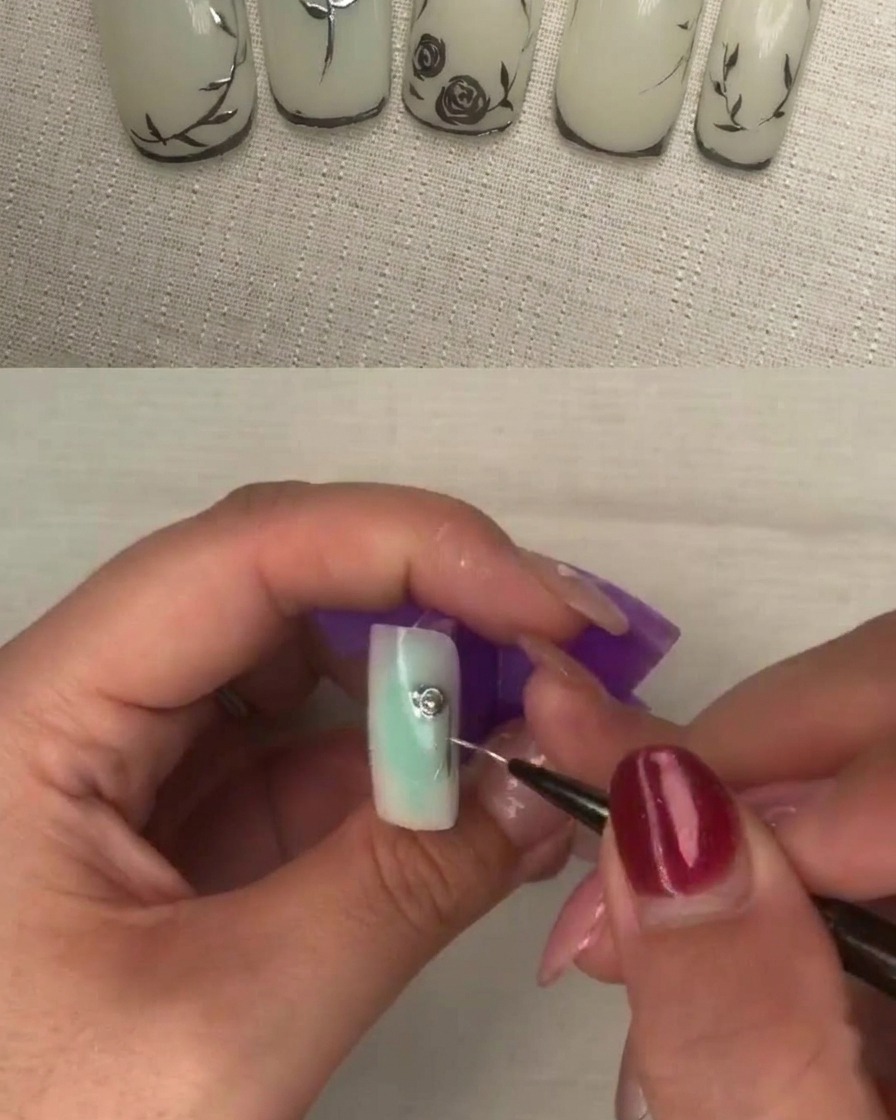 Gros plan dun pinceau liner appliquant du gel métallique épais au centre dun design de pétale sur un ongle blanc.