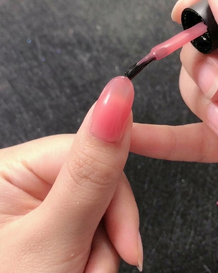 Un pinceau liner fin prélevant une petite perle de gel de construction transparent dans le pot.