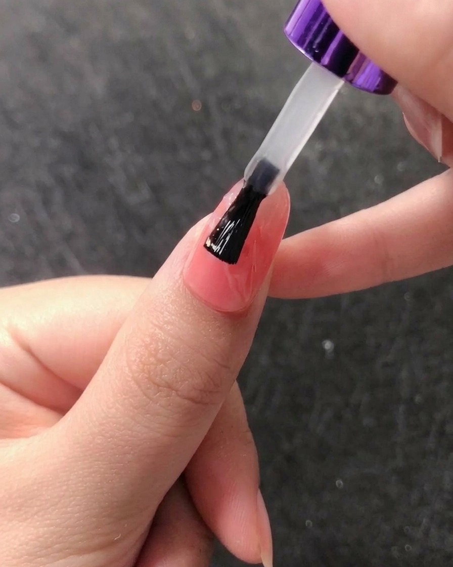 Un applicateur éponge frottant de la poudre chrome or rose sur un ongle pour créer un effet miroir.