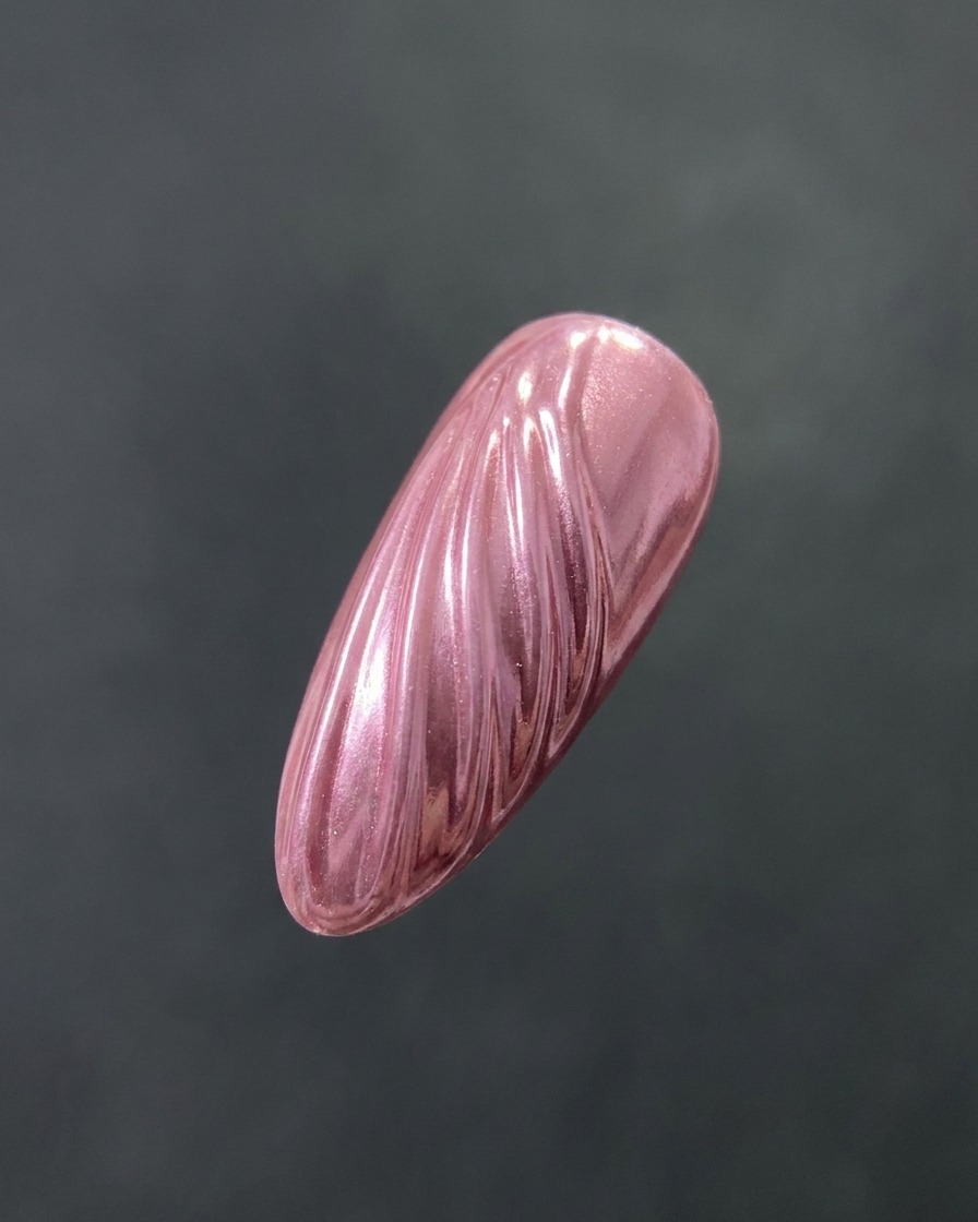 Un pinceau appliquant un top coat transparent et brillant sur un ongle texturé à la finition chrome.