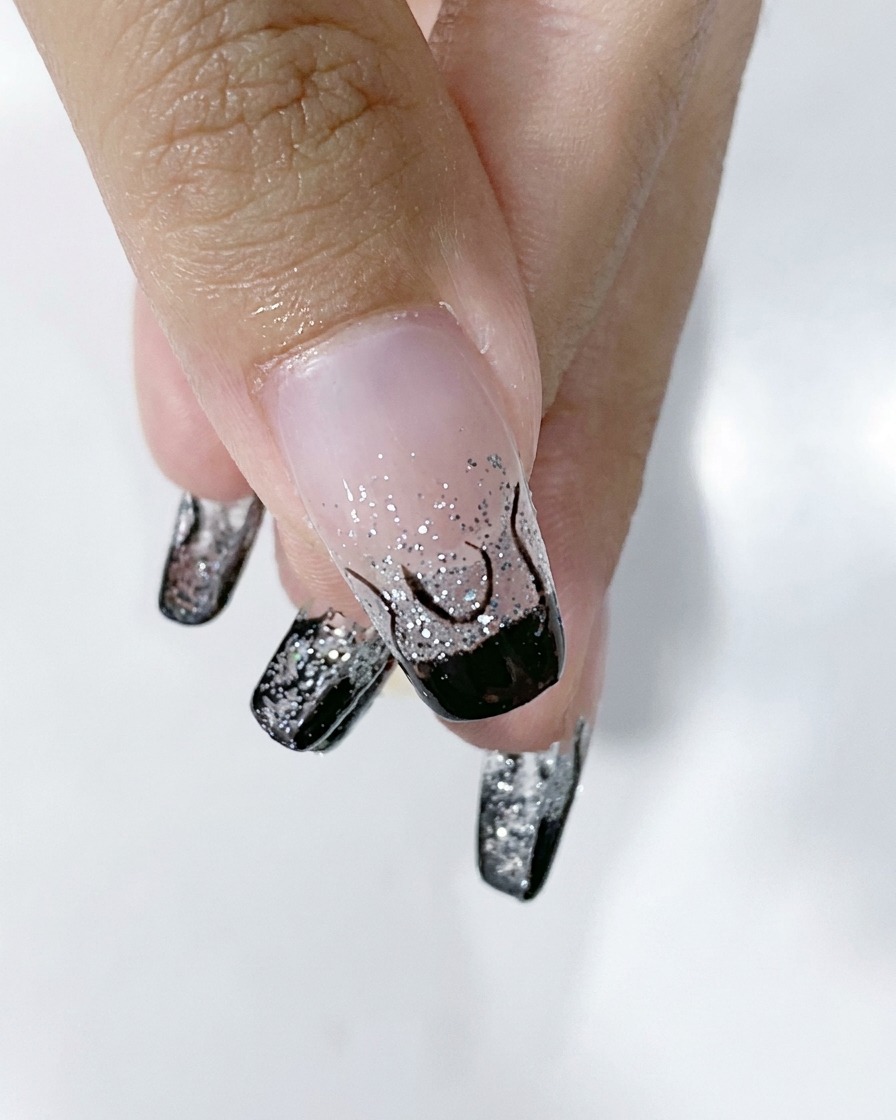 Gros plan dun ongle montrant le contour complet dune flamme noire sur une base dégradée argentée.
