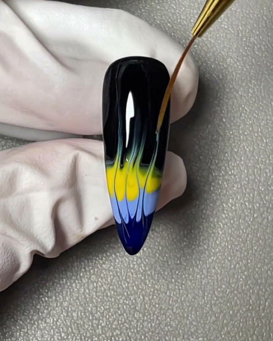 Une bande horizontale de vernis gel jaune appliquée juste au-dessus de la bande bleue sur le bout de longle.