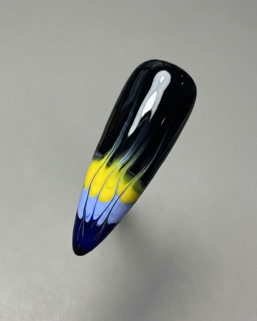 Un pinceau liner fin tirant les gels bleu et jaune vers le haut pour créer la base du motif de flammes.