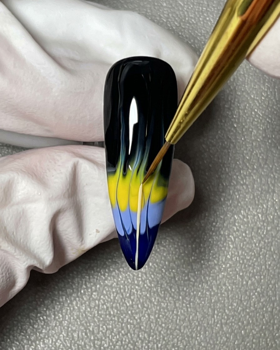 Un gros plan dun pinceau à ongles tirant des lignes fines depuis les formes de flammes colorées vers la zone de la cuticule.