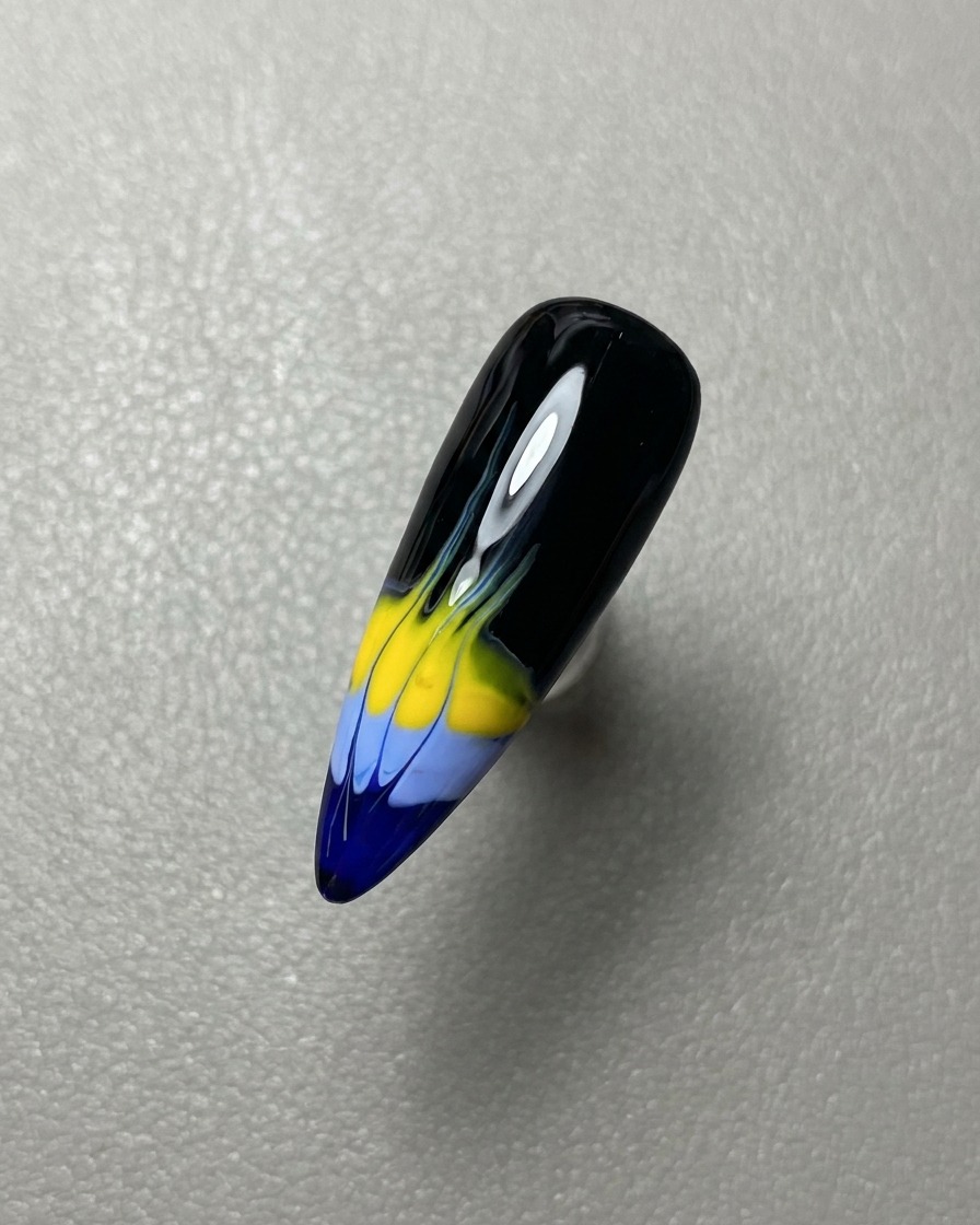 Un pinceau appliquant une couche de vernis gel top coat brillant transparent sur le nail art flammes terminé.