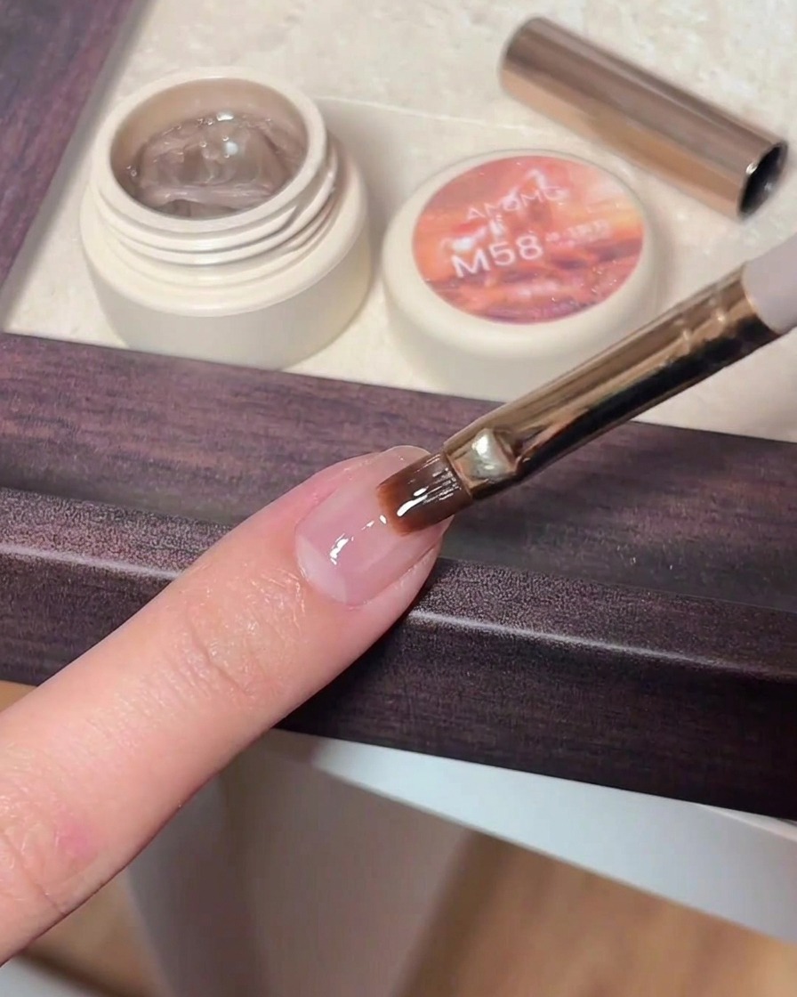 Une pince déposant une petite étoile scintillante sur un ongle recouvert de top coat non catalysé.