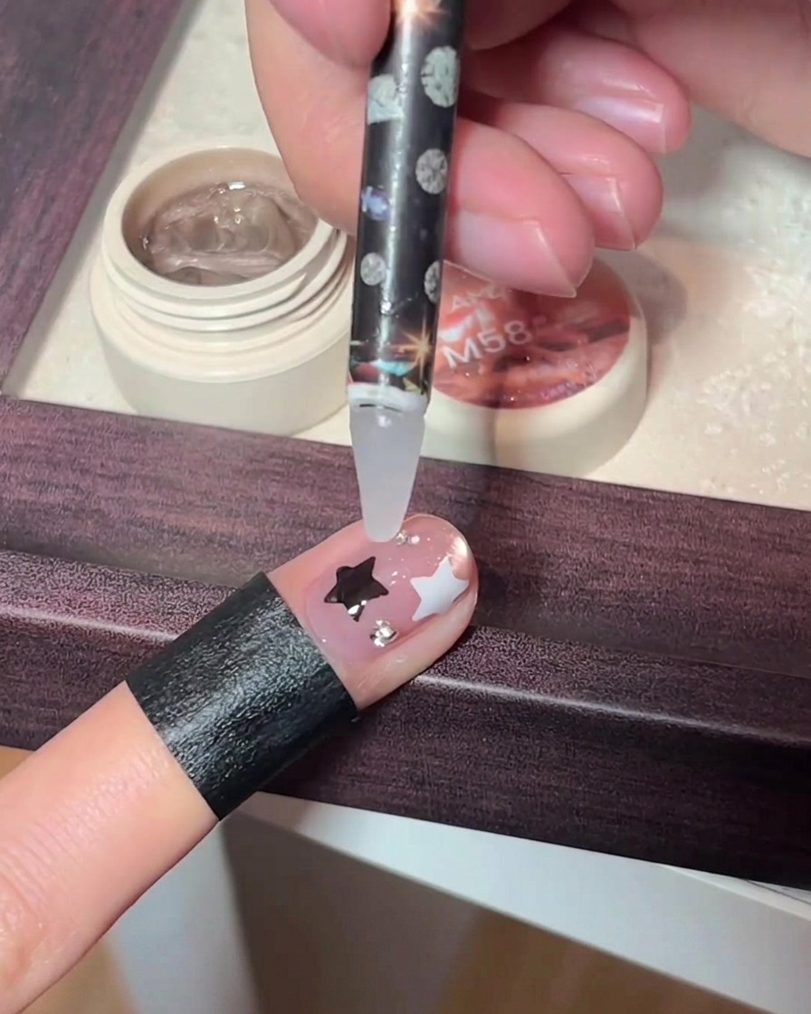 Un outil de précision déposant de minuscules strass sur un ongle décoré.
