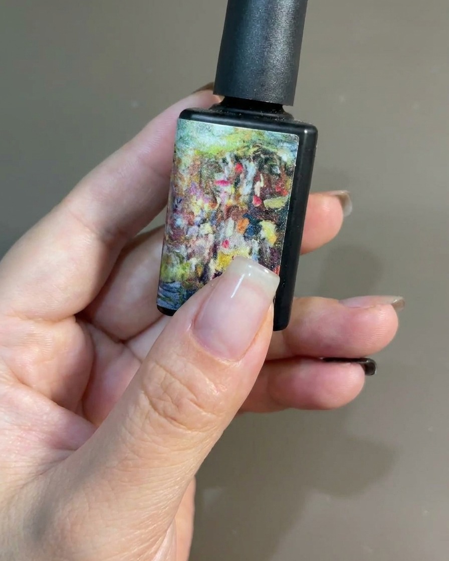Un pinceau appliquant une couche uniforme de vernis gel noir sur un ongle naturel.