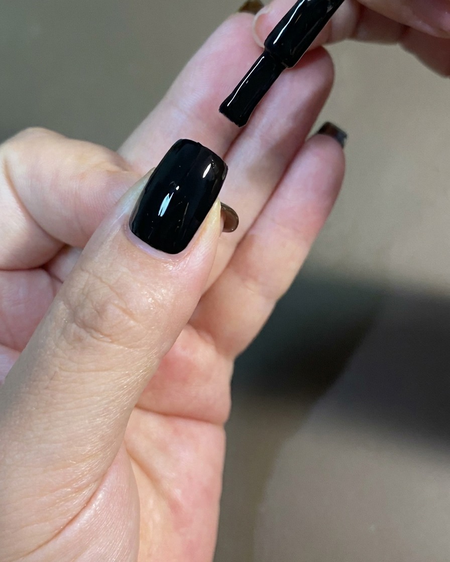 Une main placée sous une lampe UV professionnelle pour catalyser le vernis.