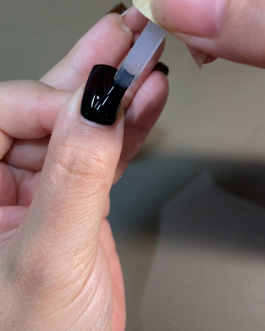 Une main manucurée catalysant la dernière couche de top coat sous une lampe à ongles UV professionnelle.