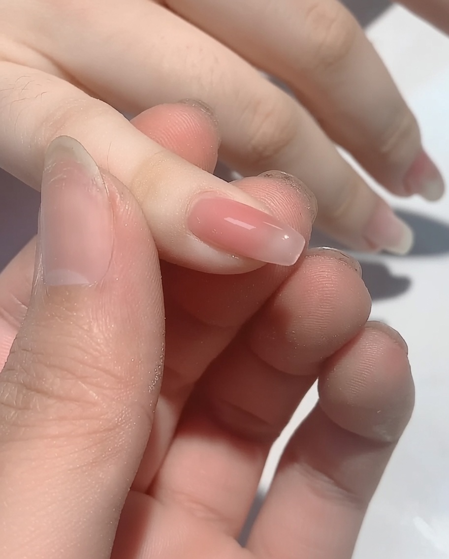 Gros plan dun embout mousse appliquant de la poudre irisée sur la pointe dun ongle vernis.
