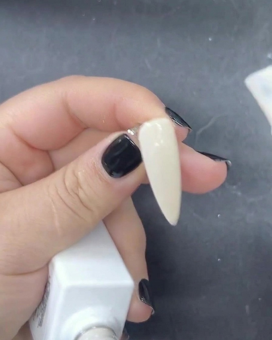 Vue en gros plan dun pinceau appliquant un vernis gel blanc laiteux diaphane sur un ongle.