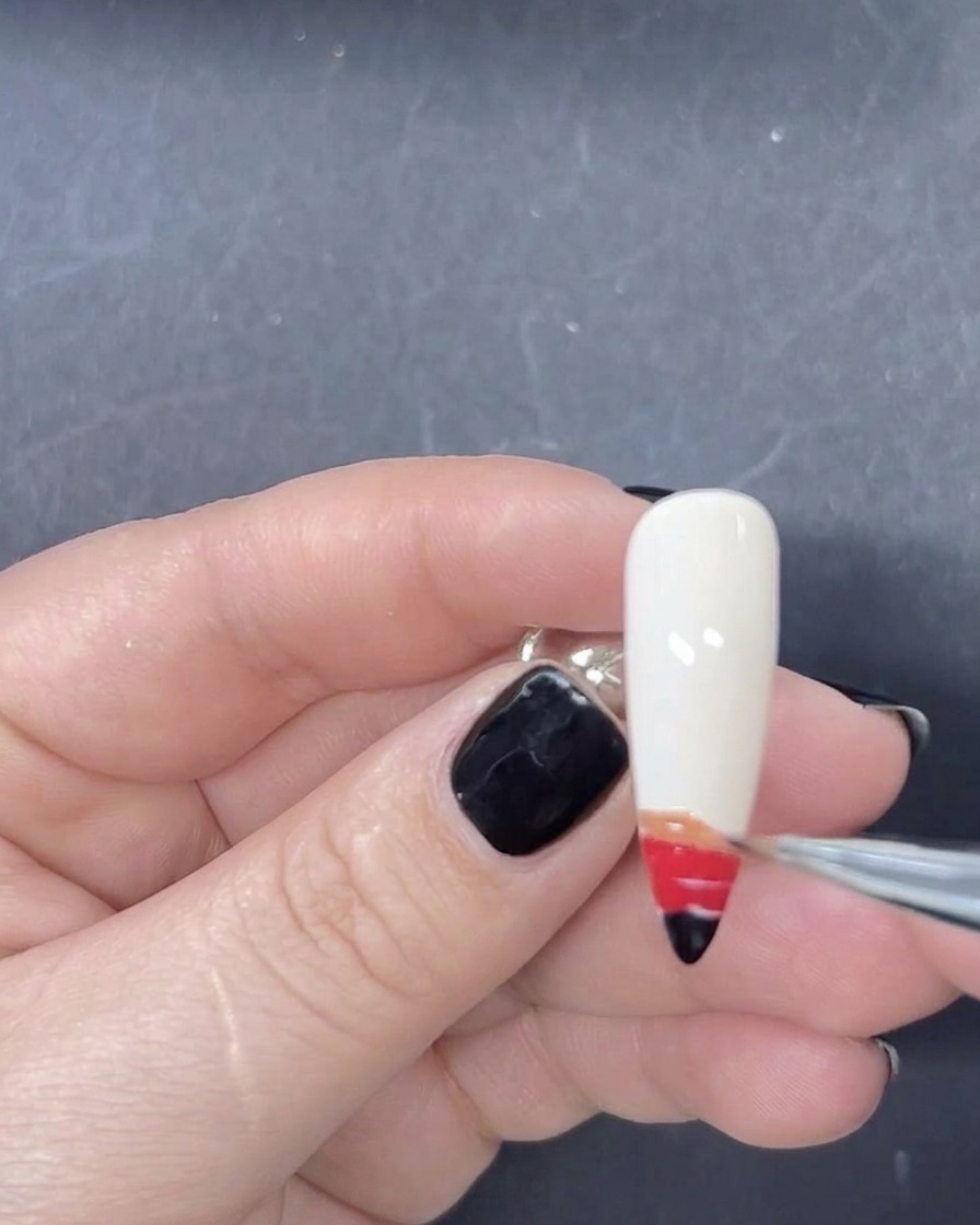 Un pinceau liner fin ajoutant une bande orange de vernis gel à la séquence de dégradé sur longle.
