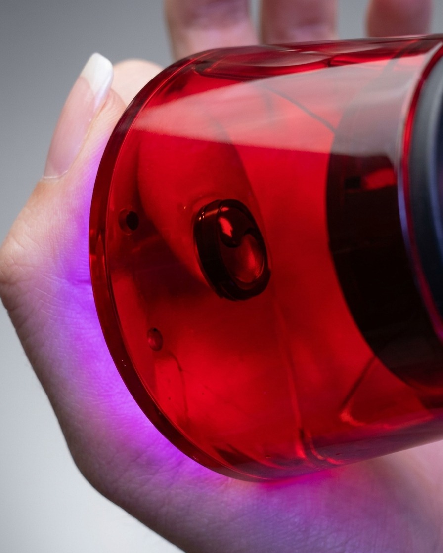 Gros plan dune main tenant une lampe à ongles UV/LED compacte rouge directement au-dessus dun doigt pour catalyser le vernis gel.