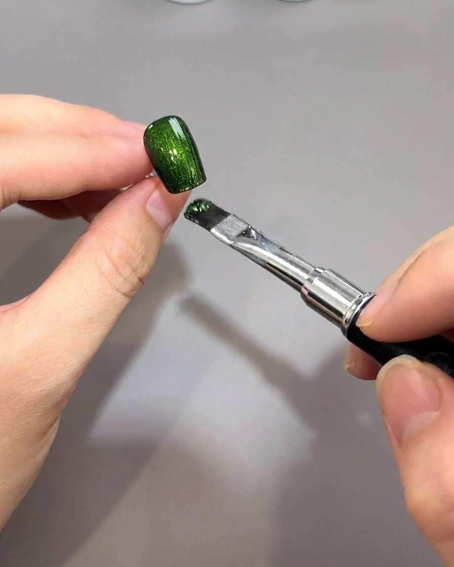 Un pinceau applique un gel magnétique vert émeraude vibrant sur une base dongle noire.