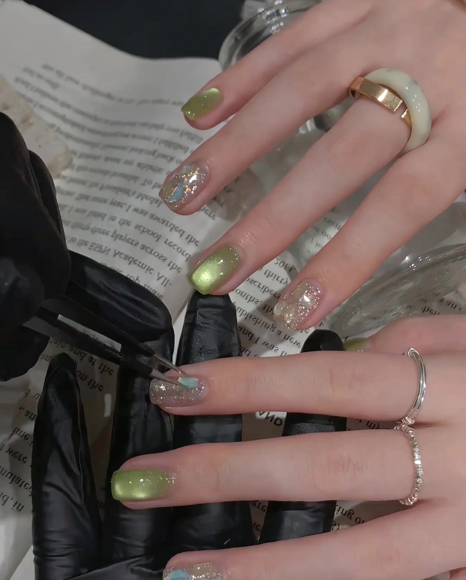 Un pinceau appliquant une couche de finition transparente et brillante sur un ongle décoré de strass.