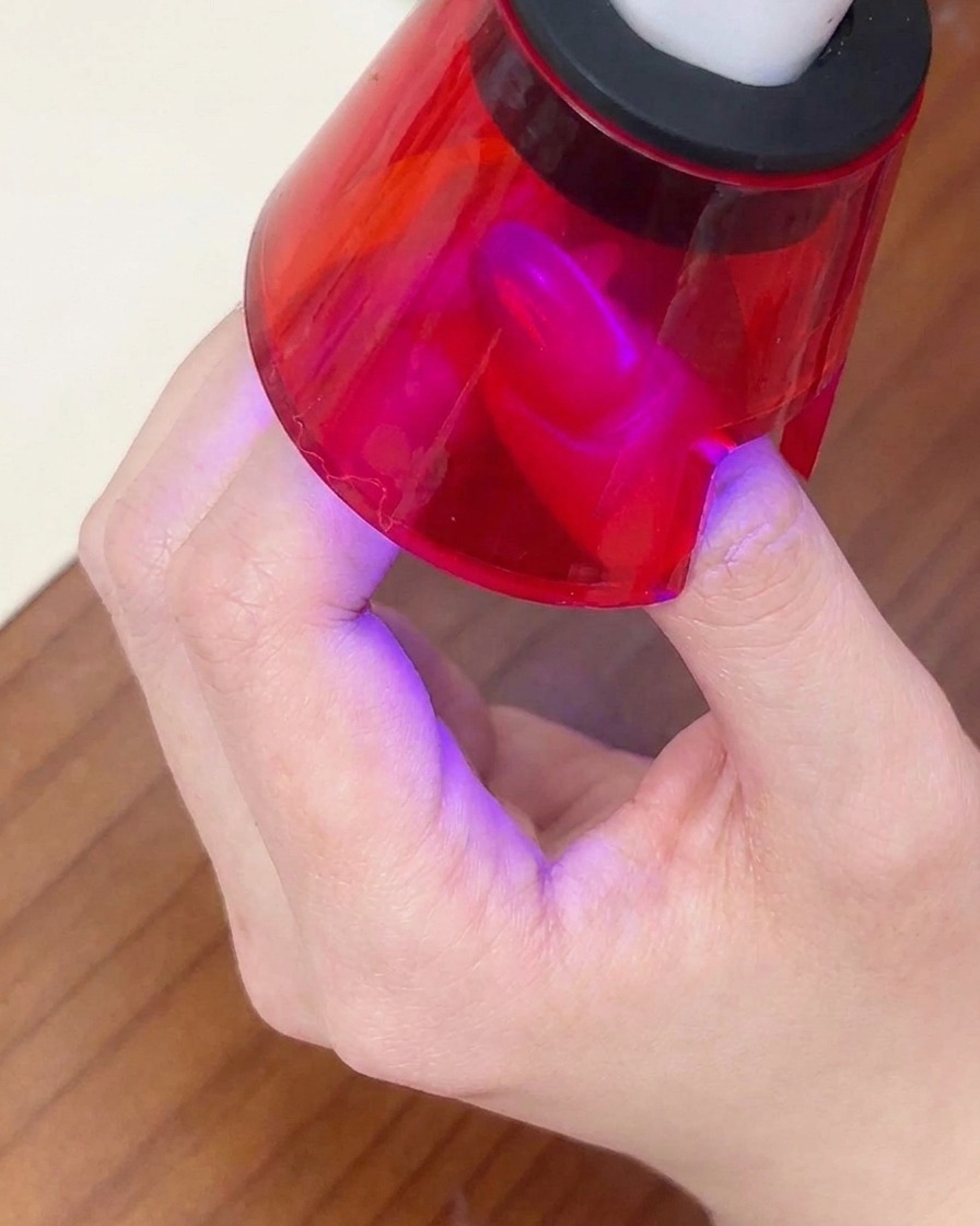 Un ongle terminé étant catalysé sous une petite lampe UV portable rouge.