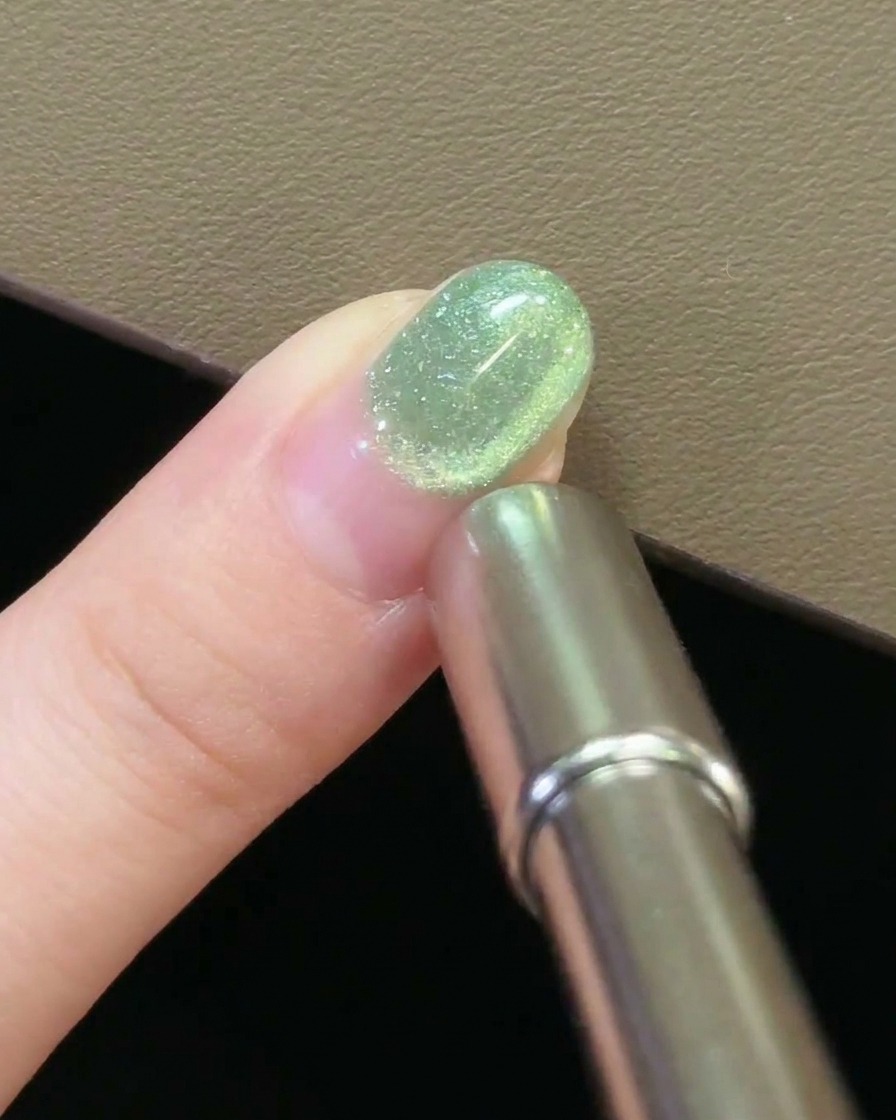 Gros plan dun aimant survolant un ongle, créant un mouvement circulaire dans le gel cat-eye.