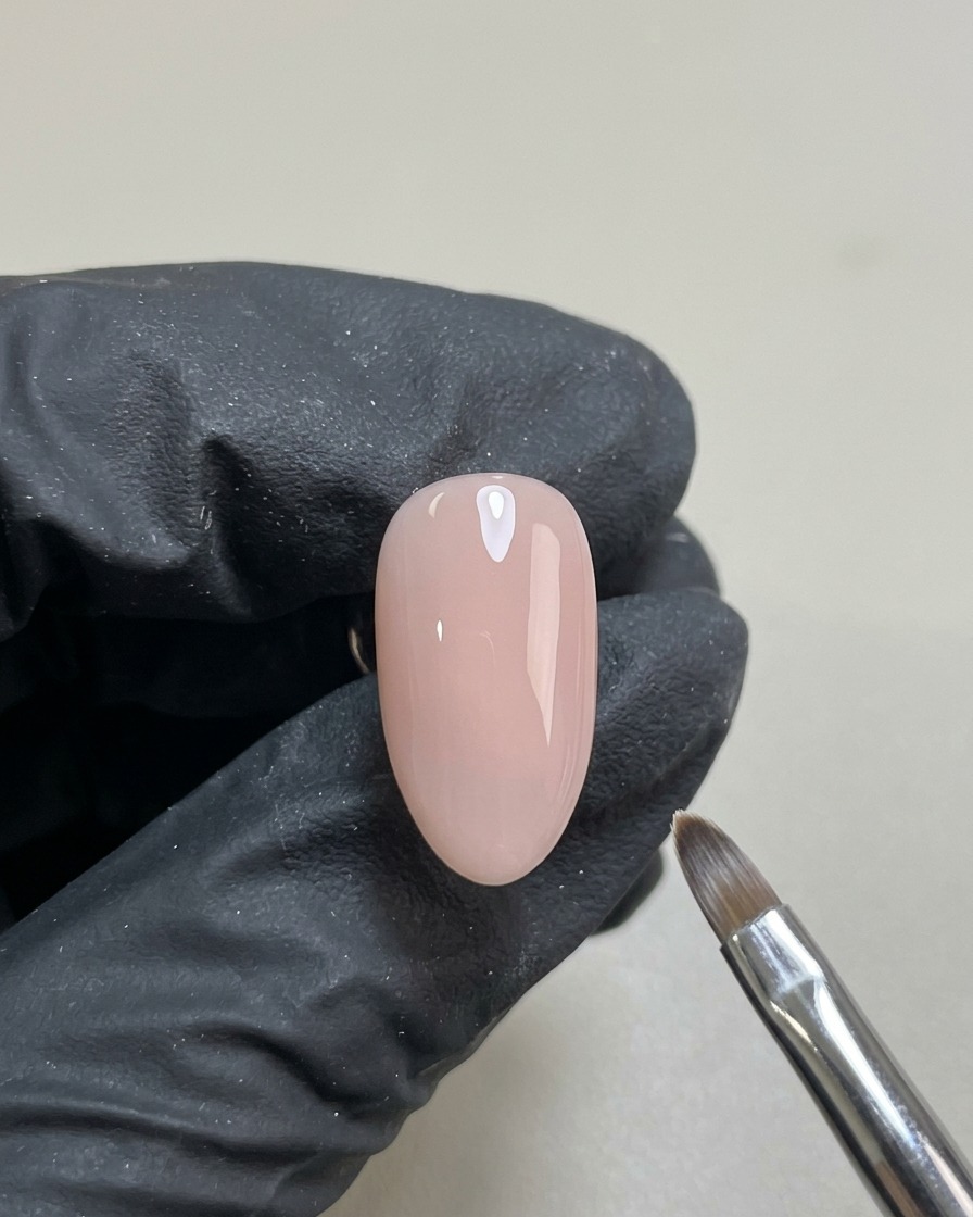 Un ongle avec une base gel nude translucide et lisse, catalysée et prête pour le nail art.