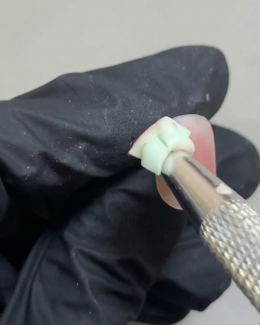 Une petite éponge estompant doucement les bords dun point de gel rose pour créer un dégradé blush doux.