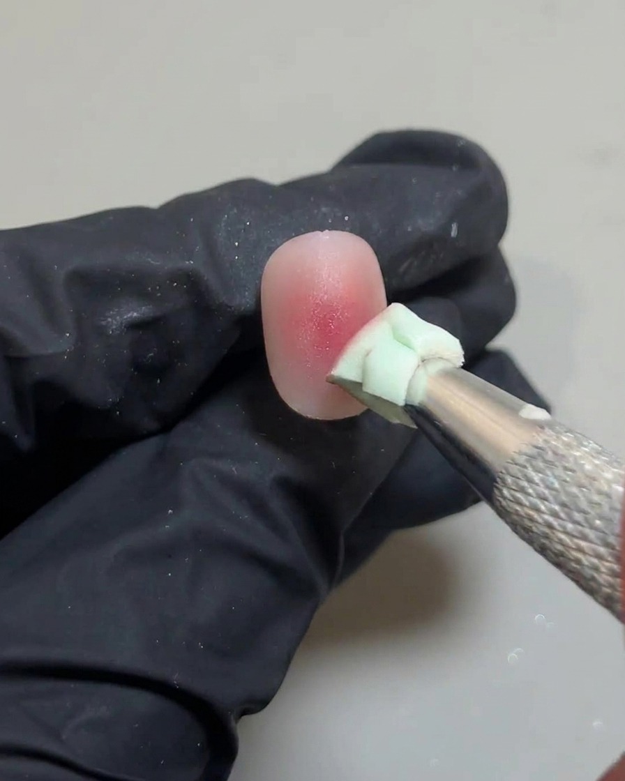 Une éponge tapotant légèrement le centre de longle pour estomper le dernier point de gel rose.