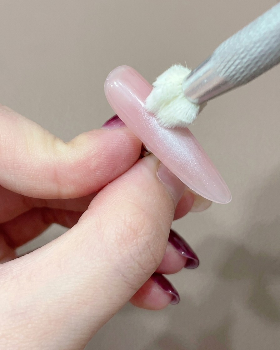 Un outil applicateur en silicone ajoutant soigneusement un point concentré de gel rose au centre de longle.