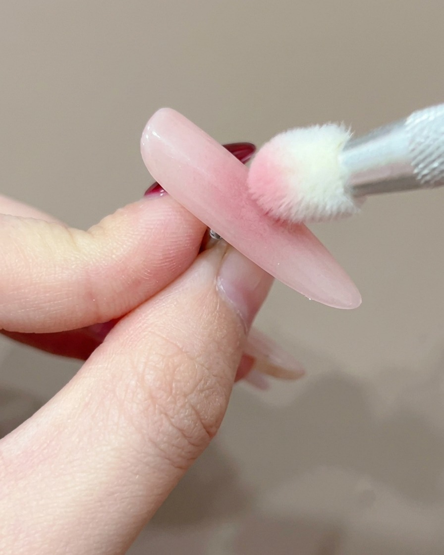 Gros plan du bout dun ongle positionné sous une lampe UV pour la catalysation.