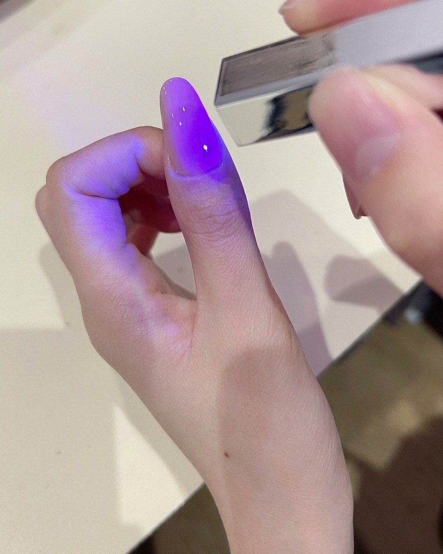 Une main utilisant une lingette non pelucheuse pour nettoyer la surface dun ongle en gel catalysé.