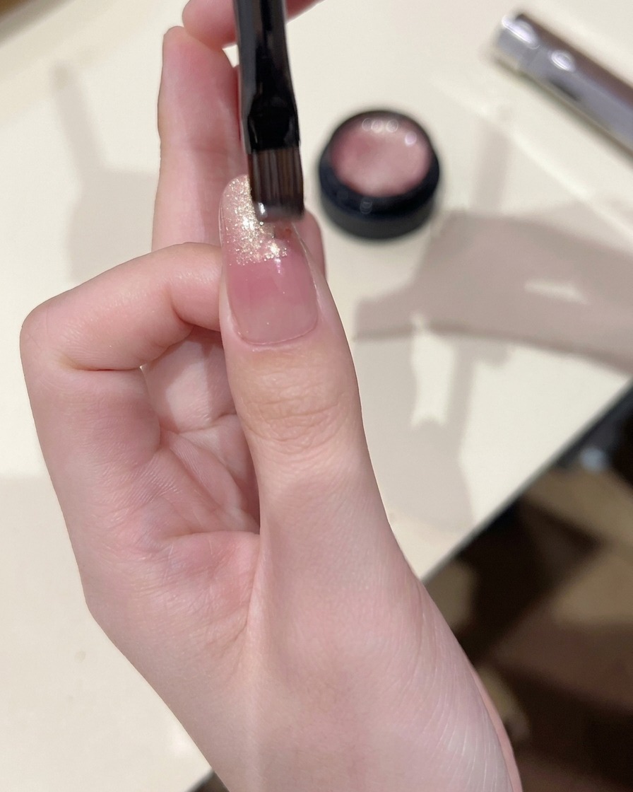 Un petit pinceau à ongles appliquant du gel cat eye sur la pointe dun ongle, en le mélangeant légèrement vers le bas.