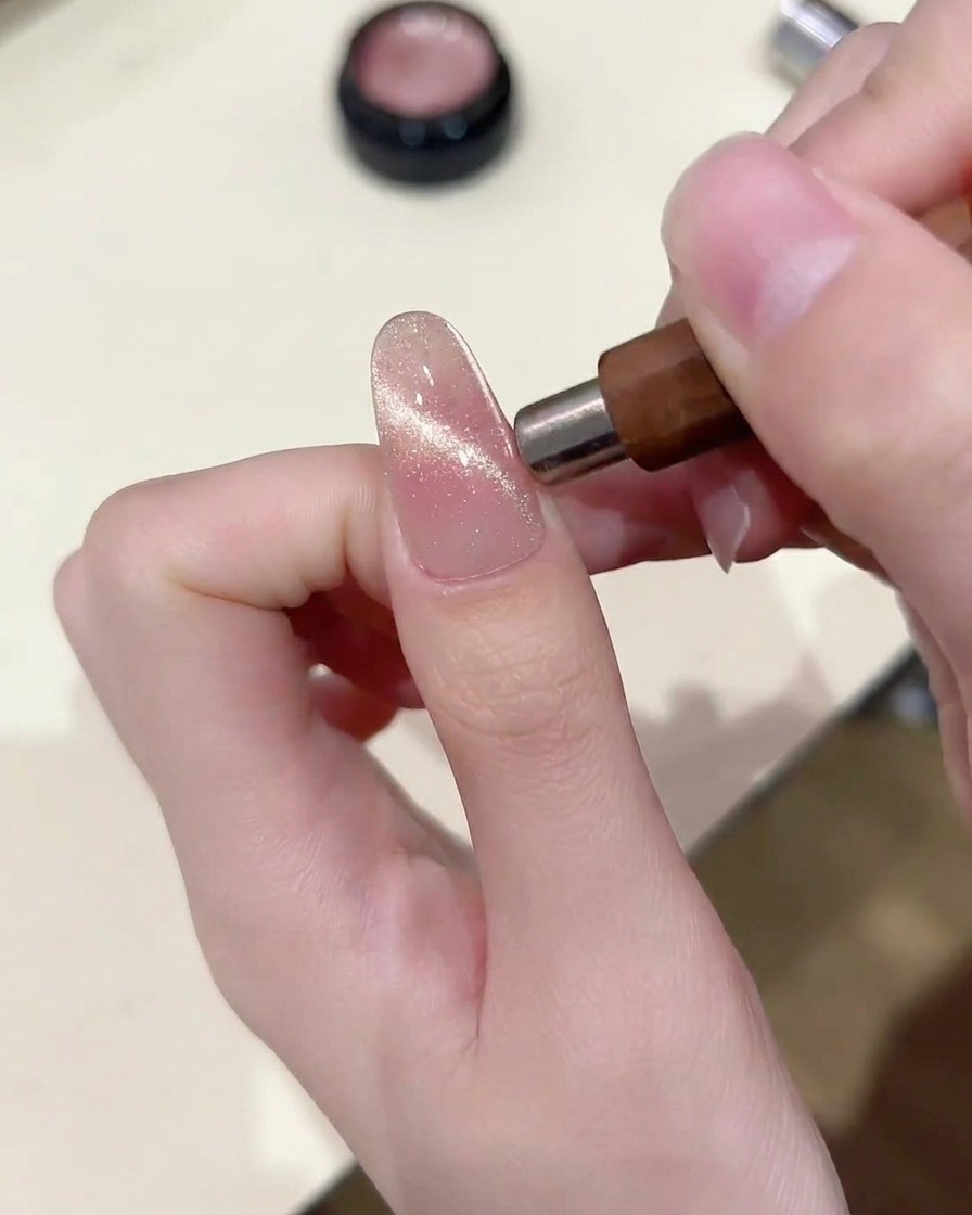 Un outil aimanté tenu parallèlement à longle, concentrant les particules cat eye en une bande horizontale lumineuse.