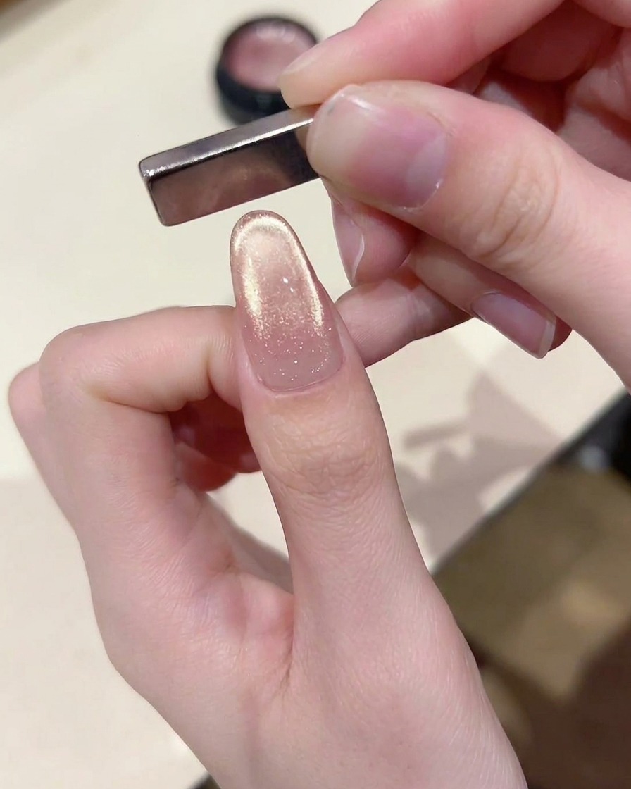 Un outil aimanté incliné au-dessus de la pointe de longle, créant une ligne de lumière incurvée style French.