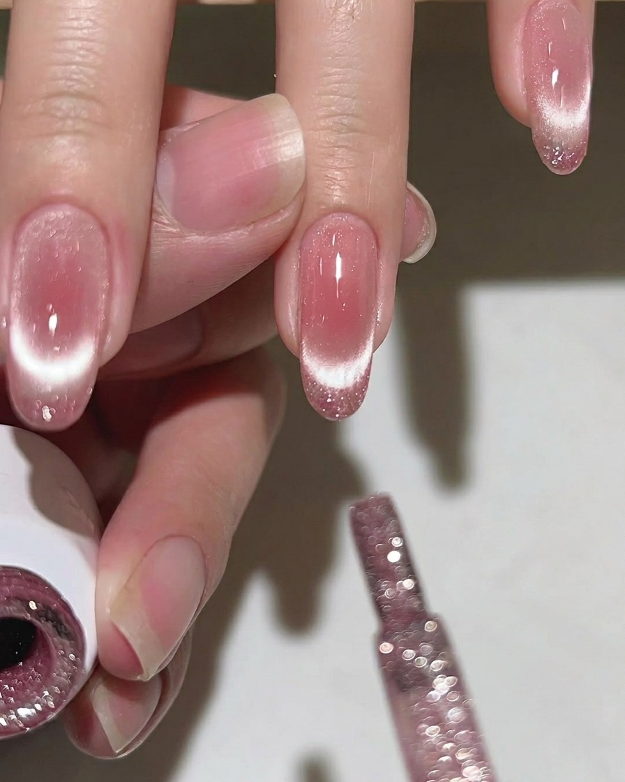 Un pinceau appliquant une fine couche de vernis pailleté sur la pointe de longle.