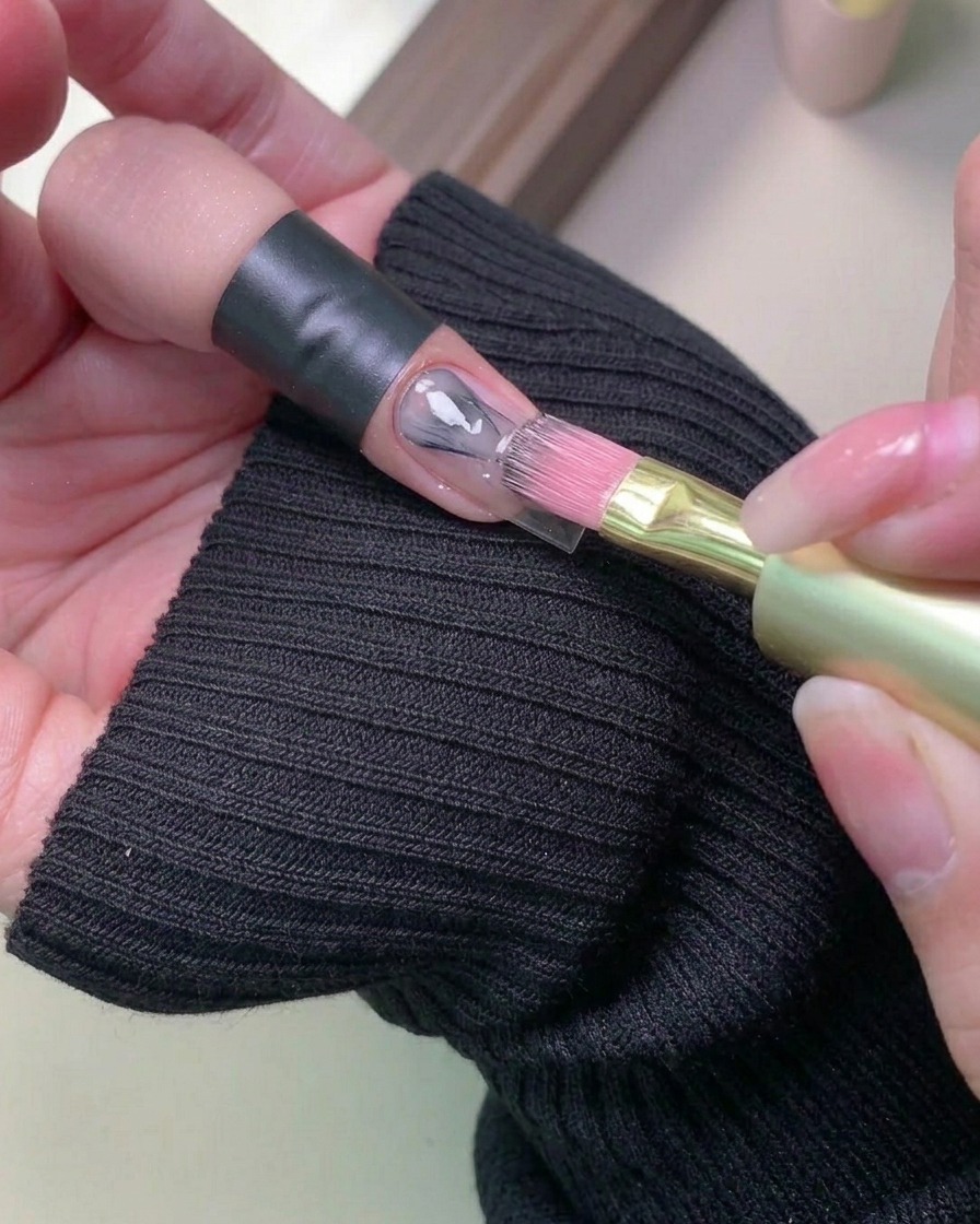 Pinceau appliquant un vernis gel clair sur un ongle naturel.