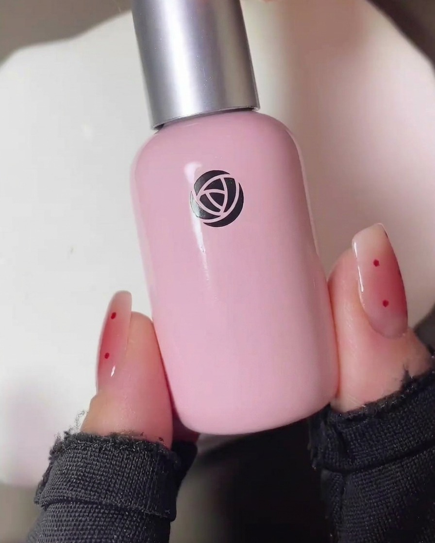 Gros plan dun pinceau tapotant une petite quantité de gel blush rouge translucide au centre dun ongle mat.