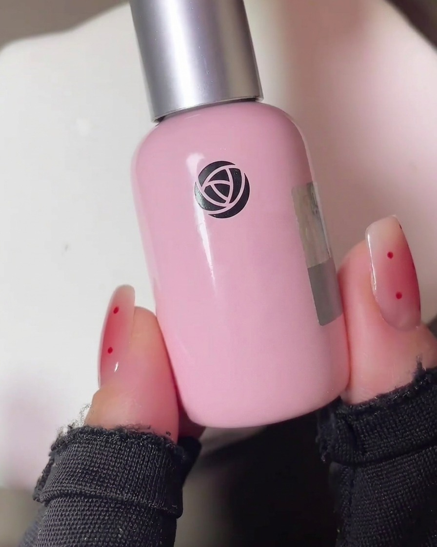 Une main avec des ongles peints au gel placée dans une lampe UV professionnelle pour la polymérisation.