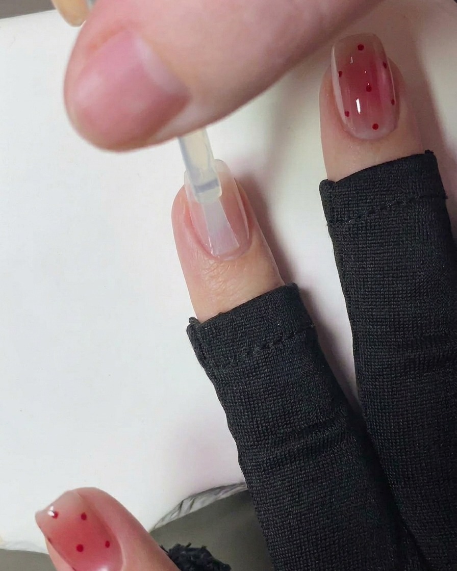Une main avec des ongles fraîchement pointillées de rouge en train de catalyser dans une lampe UV pour ongles.