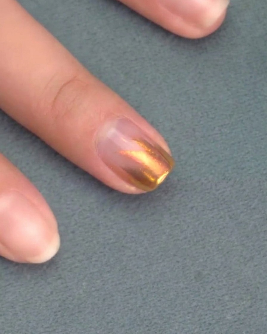 Pinceau appliquant une seconde couche de vernis gel rose sur la première.