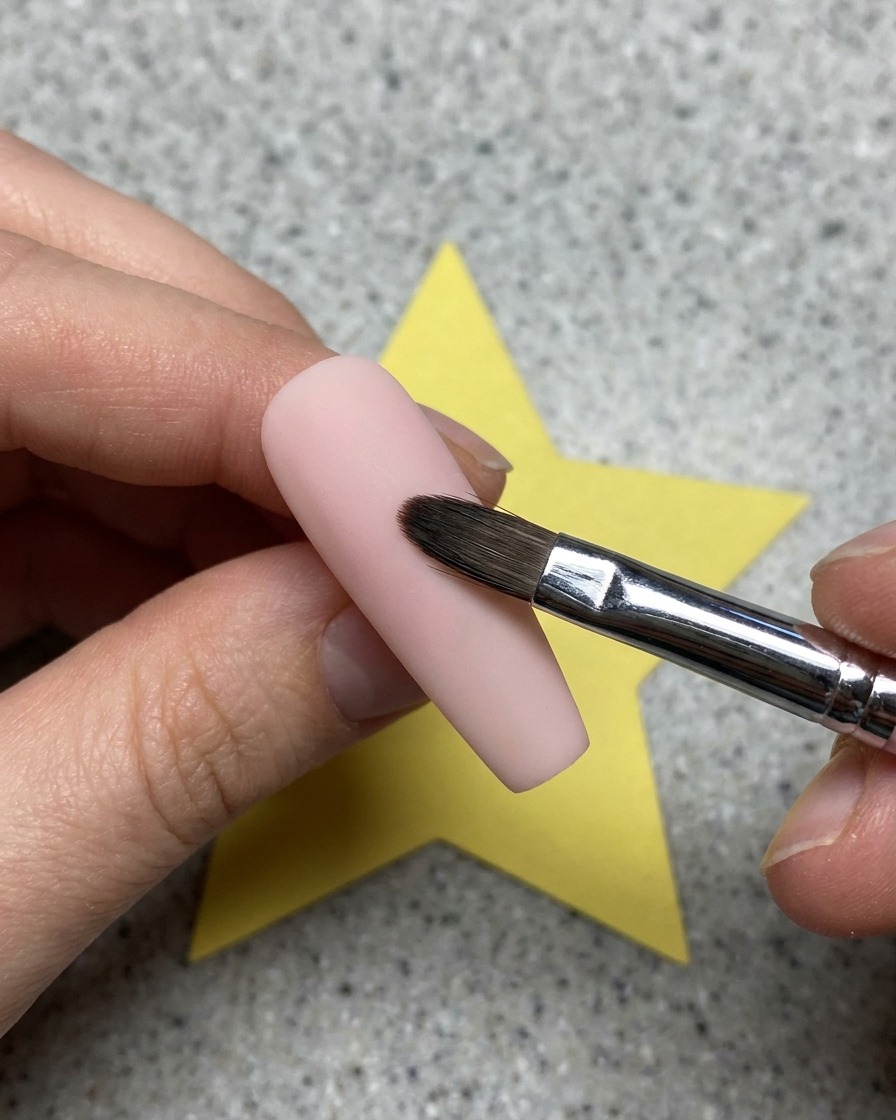 Gros plan sur un gel transparent appliqué sur une base dongle rose avec un pinceau.