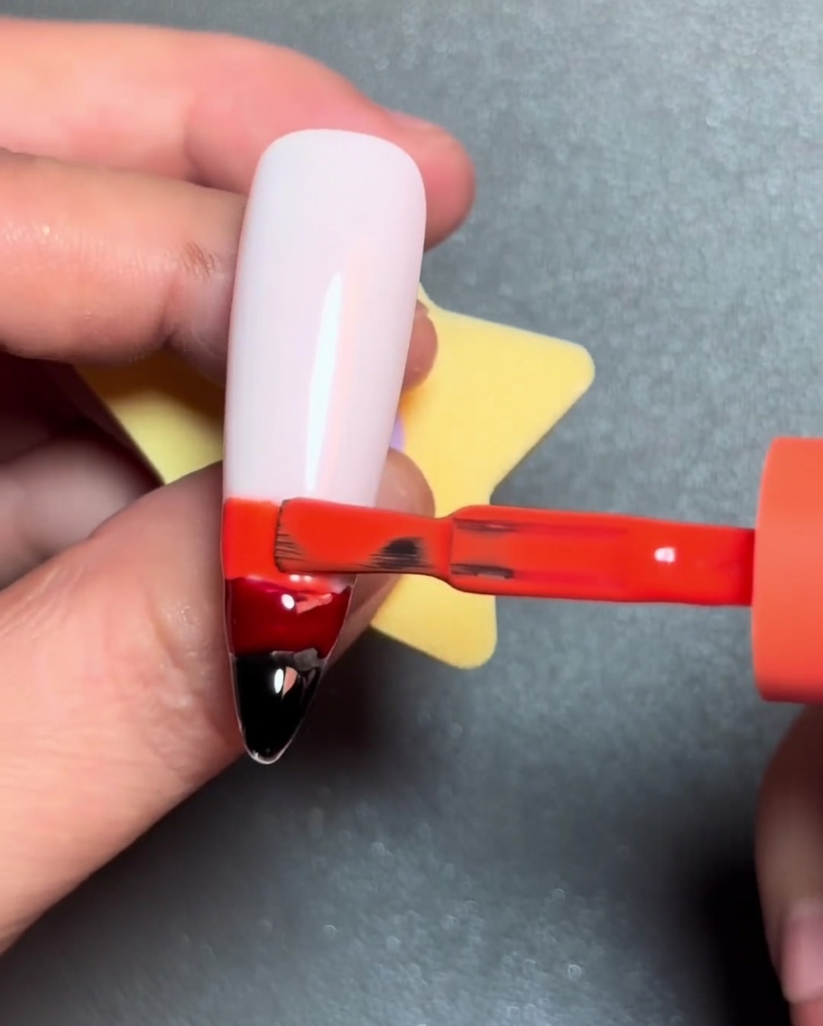 Un pinceau appliquant une ligne de vernis gel jaune au-dessus de la bande orange.