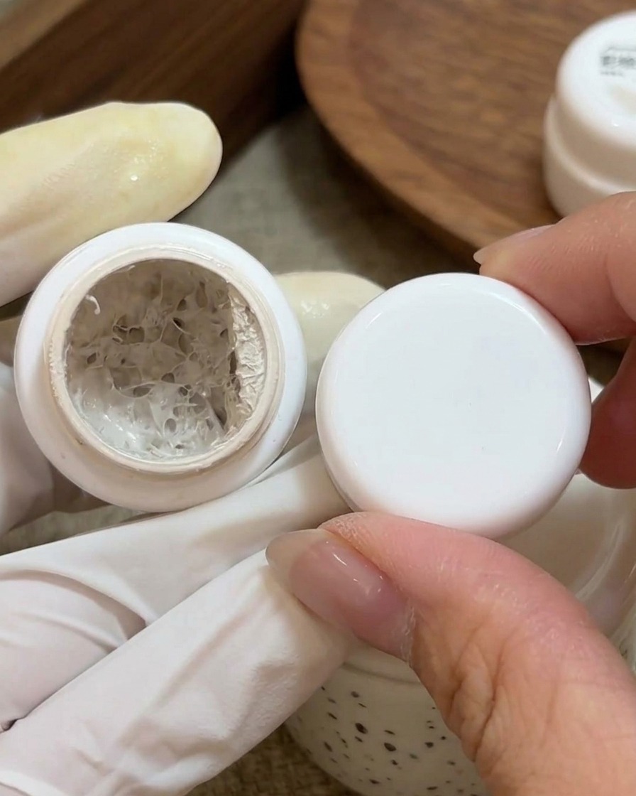 Un petit pinceau applique du gel peinture blanc sur la base dun ongle naturel préparé.