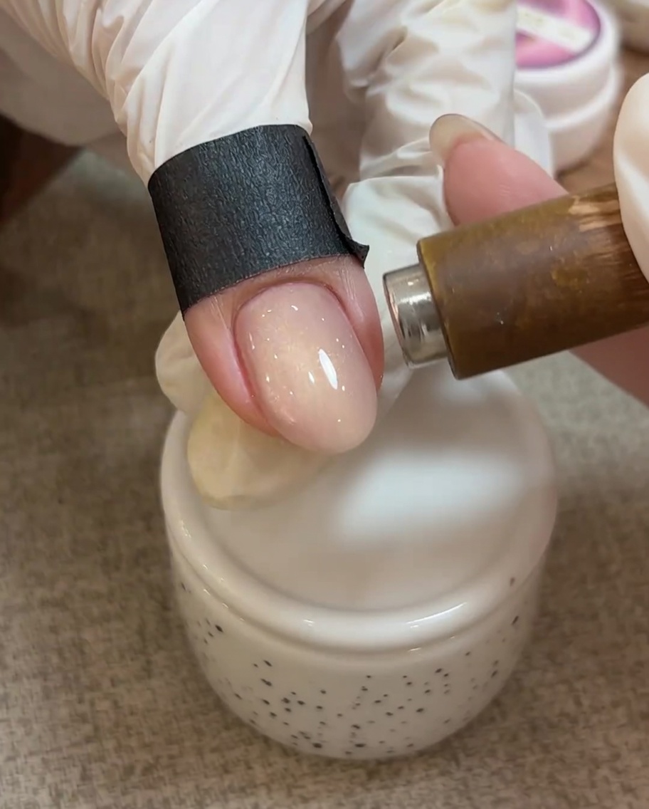 Vue rapprochée dun aimant au-dessus dun ongle avec du gel cat eye non catalysé, montrant les particules se déplaçant pour créer une ligne brillante.