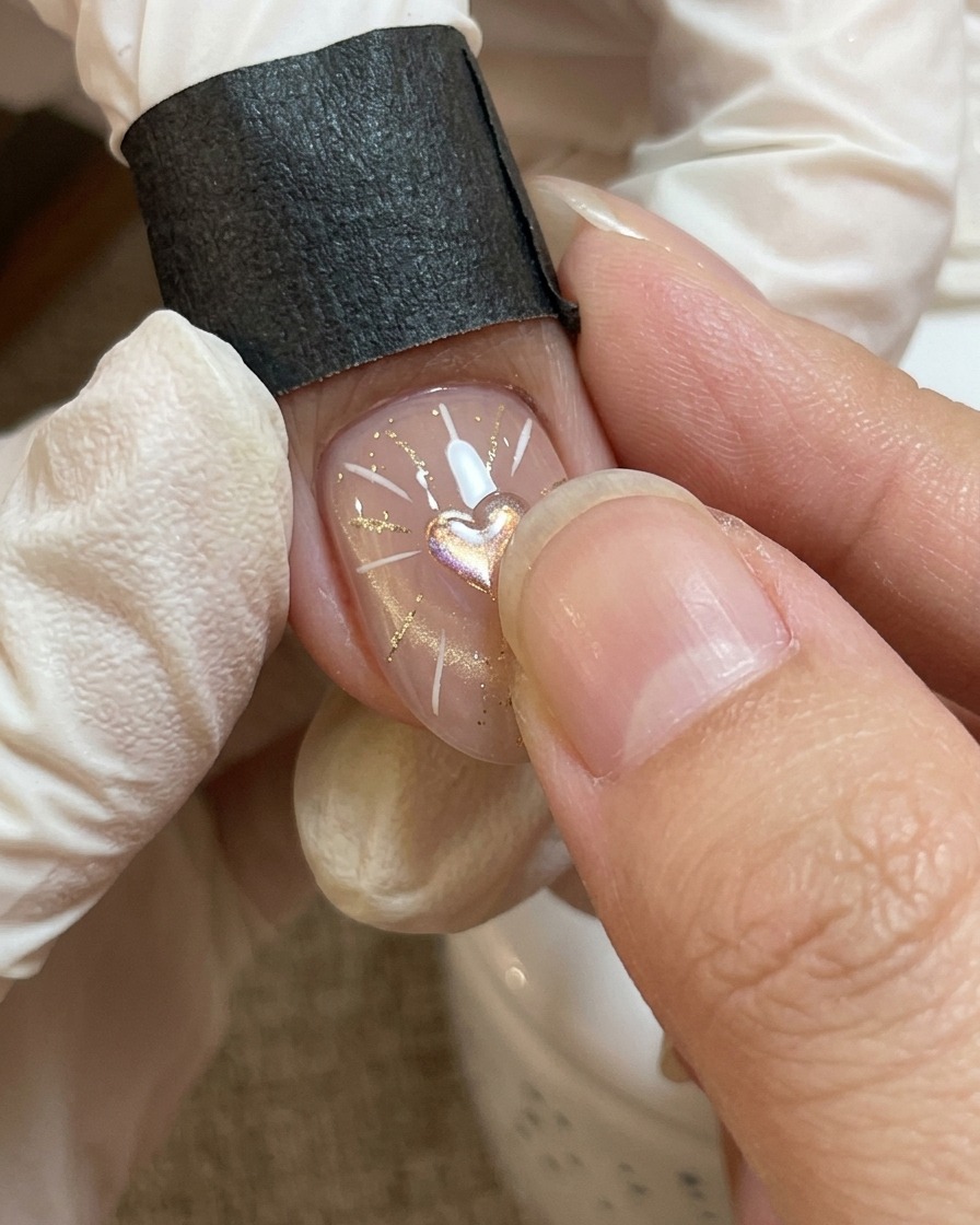 Vue rapprochée dun nail art où un gel transparent épais est placé sur le motif de cœur central.