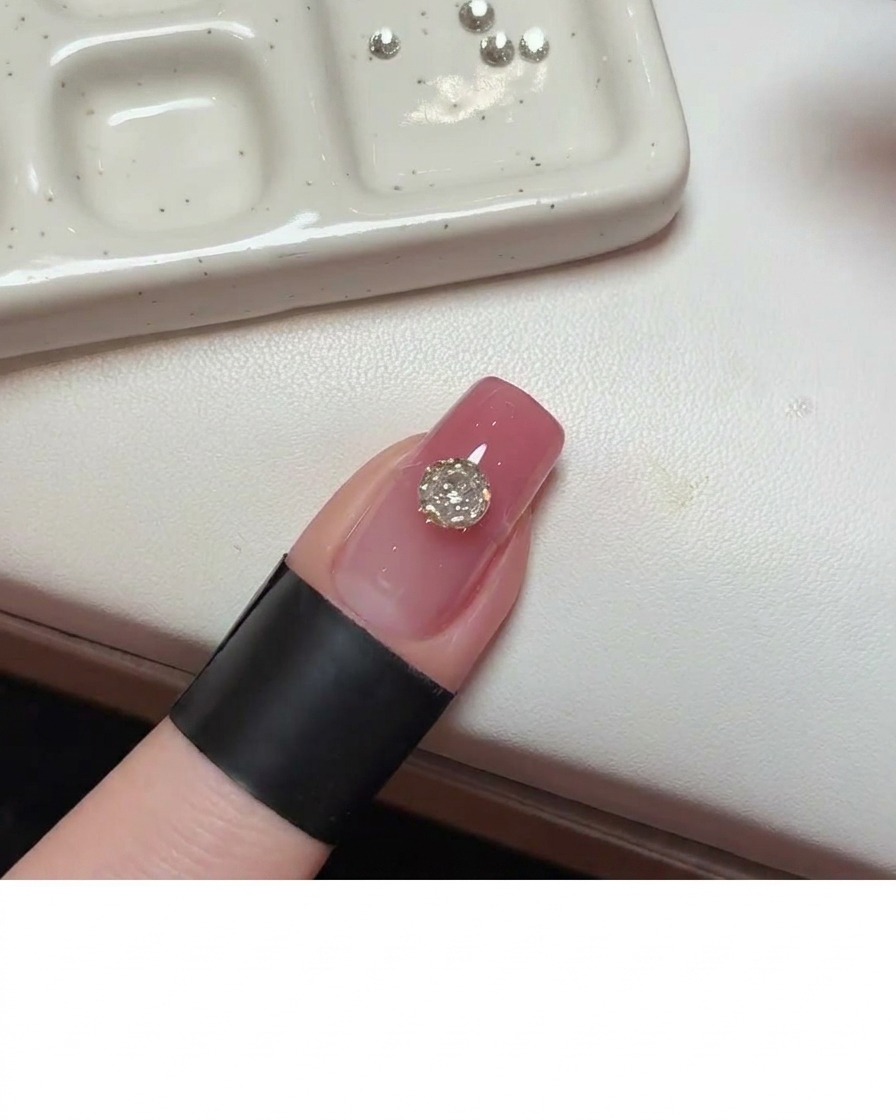 Un outil de précision appliquant du gel adhésif transparent sur la surface de longle directement à côté du cristal principal.