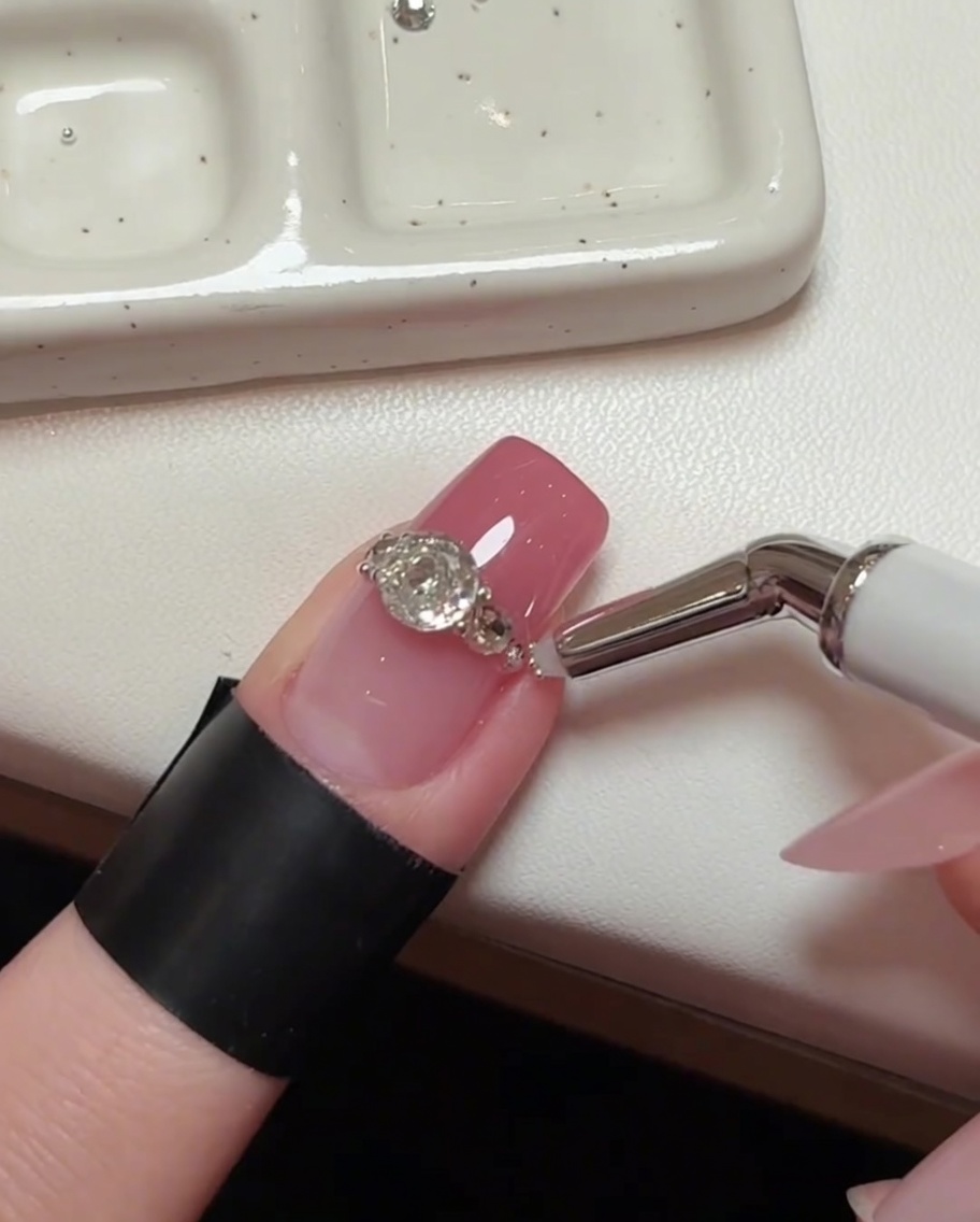 Un plan détaillé du nail art, montrant un outil de précision plaçant des billes en acier microscopiques dans les petits espaces entre les cristaux plus grands.