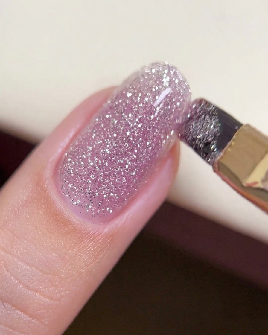 Un pinceau faisant glisser une perle épaisse de gel « crushed diamond » sur le centre dun ongle pour créer une couche uniforme et structurée.