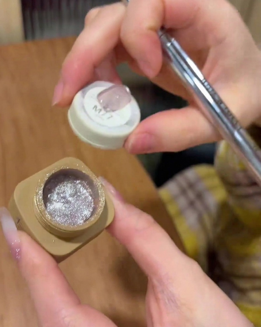 Un pinceau appliquant uniformément le vernis gel cat-eye sur la surface de longle.